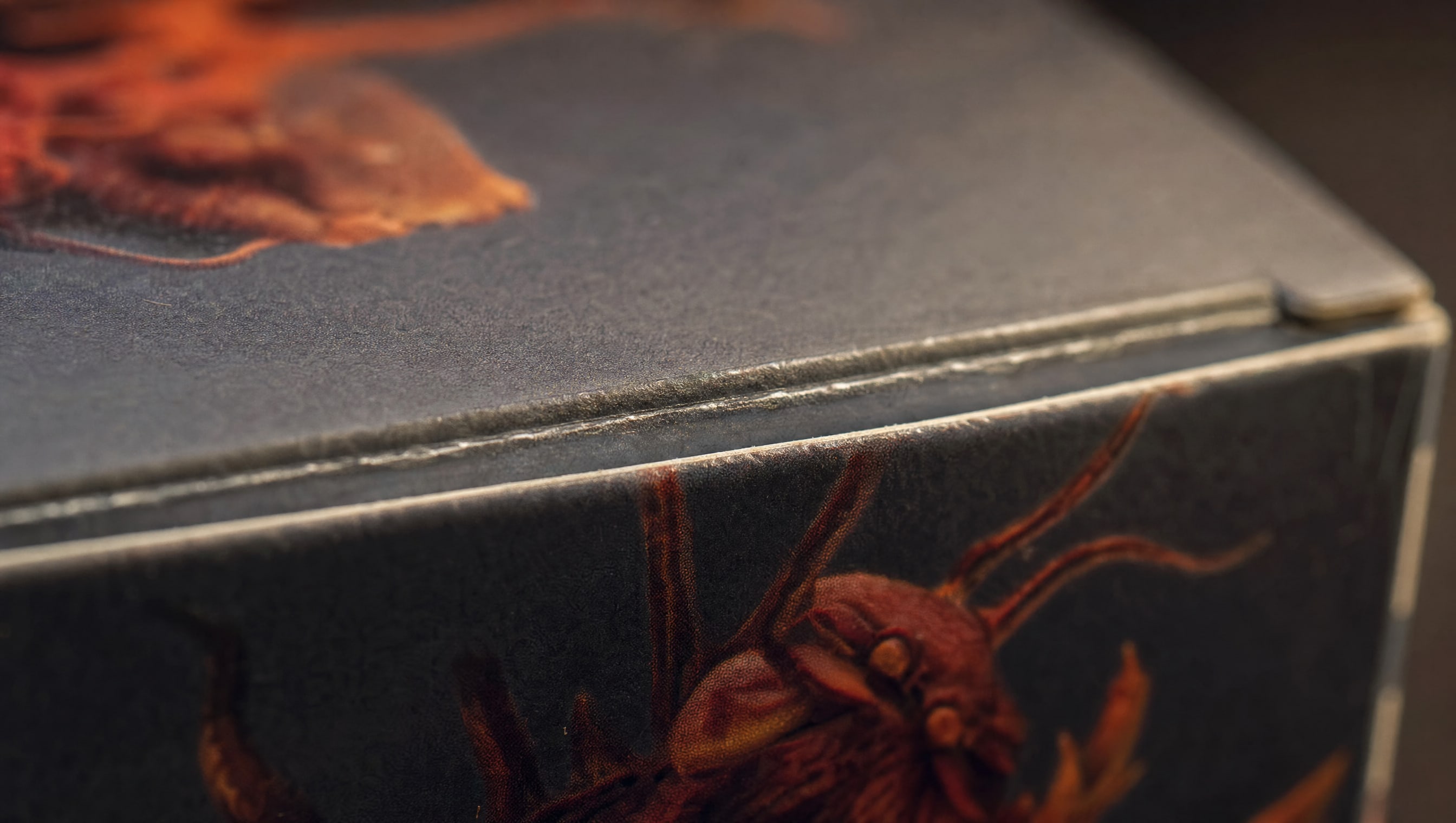 Macro on the glued lid seam of a sealed blind box, light raking across the fold.