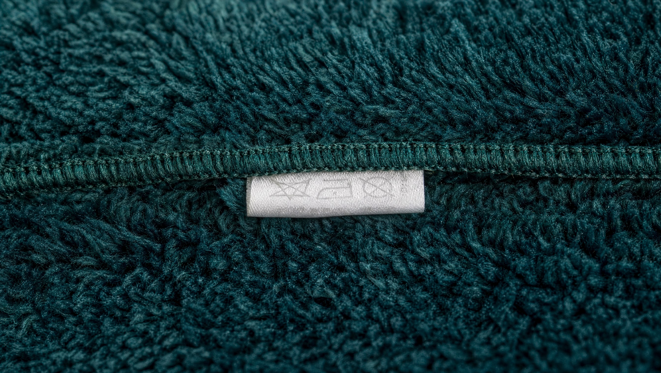 Macro on a plush seam and its sewn-in care tag, the stitches sharp.