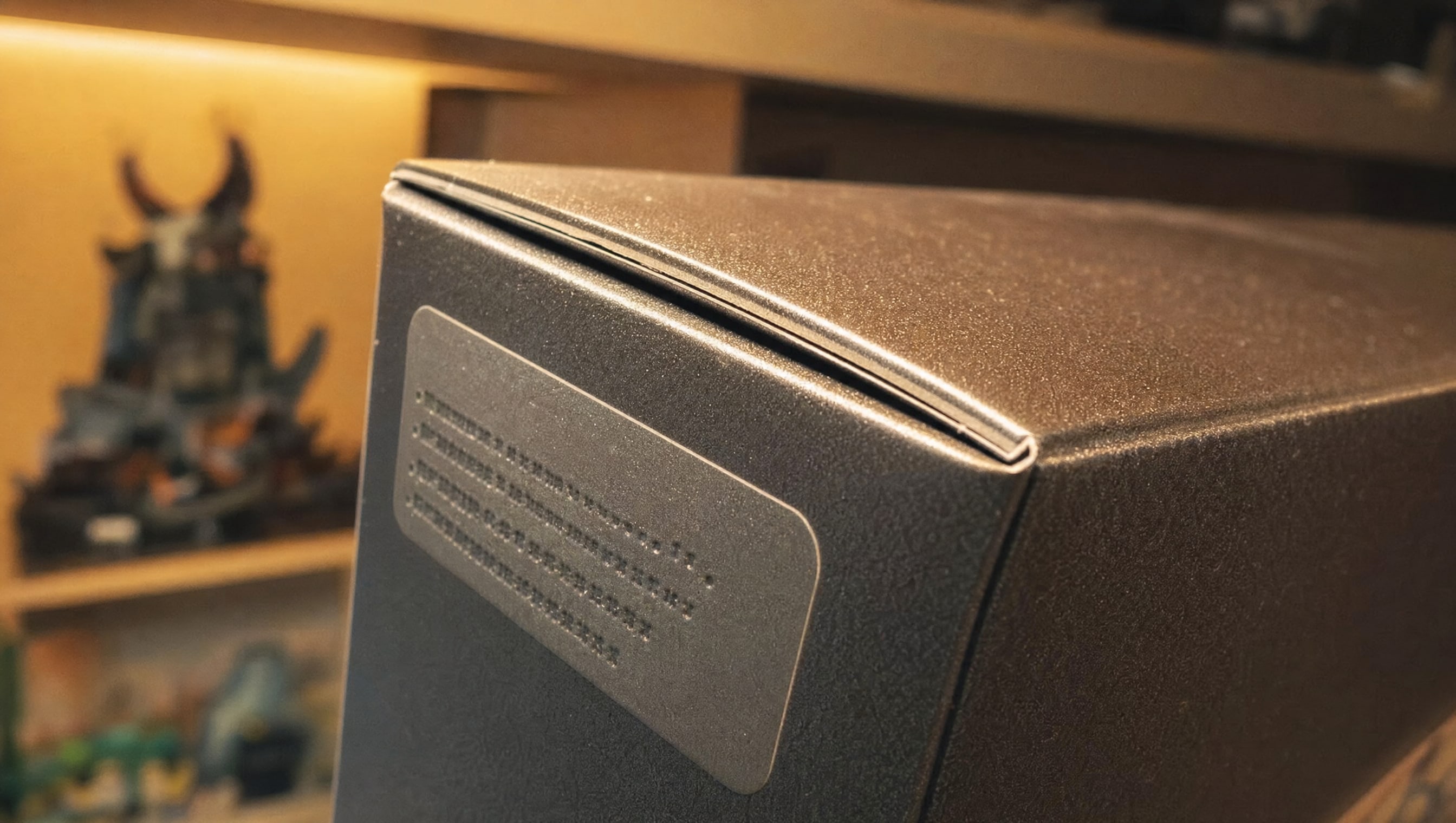 Macro on the printed corner panel of a sealed brick set box under warm shelf light, the coated card sharp and the fold of the flap catching a highlight.