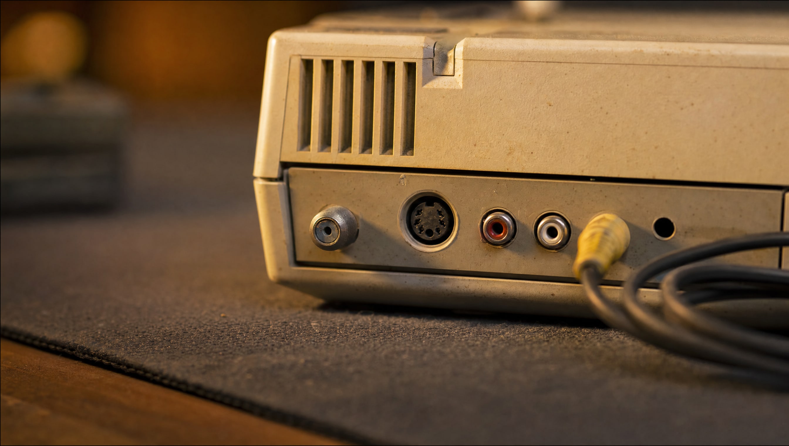 The rear panel of an invented console under a bench lamp, its output sockets catching a low raking light.
