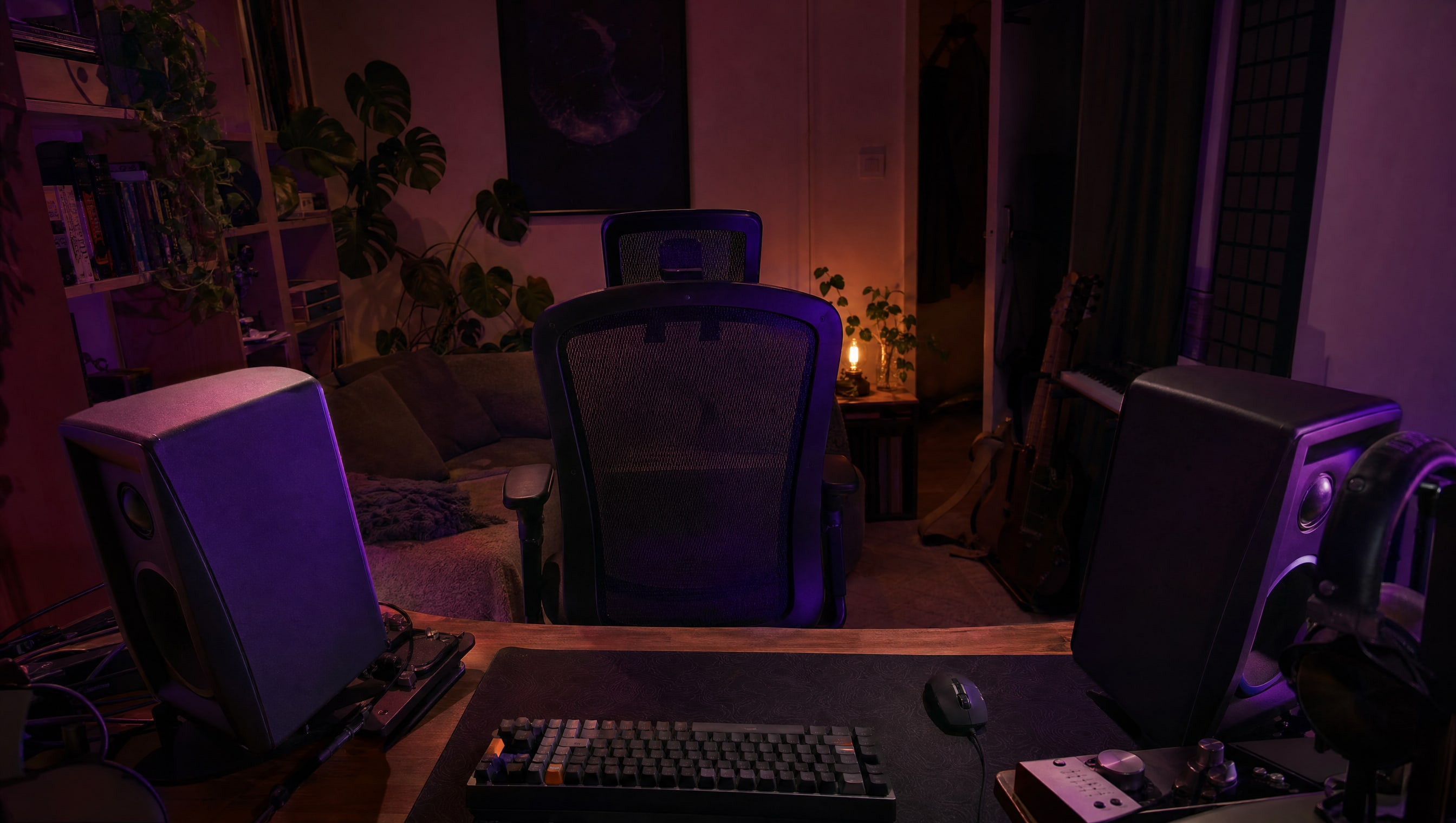 A pair of speakers angled inward toward a chair, seen from behind the desk.