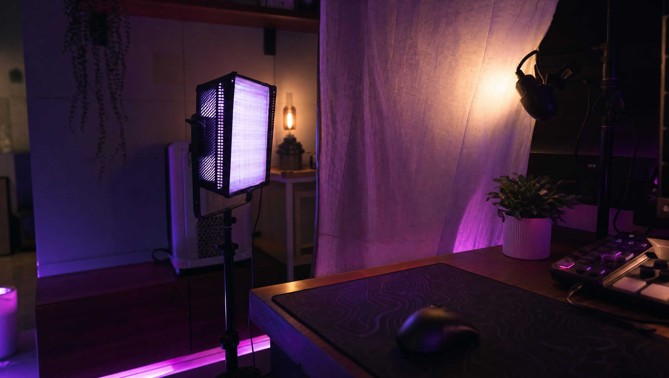 A desk corner at night: a panel light on a stand, a diffuser sheet, and a clamp light.